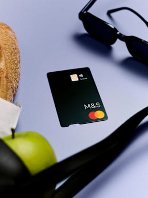 A young man in a beige knit polo shirt sitting thoughtfully on a red bench, looking to the left with a contemplative expression.