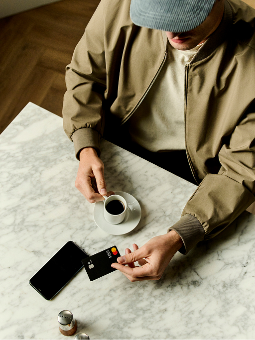 Man holding a M&S Credit Card and having black coffee