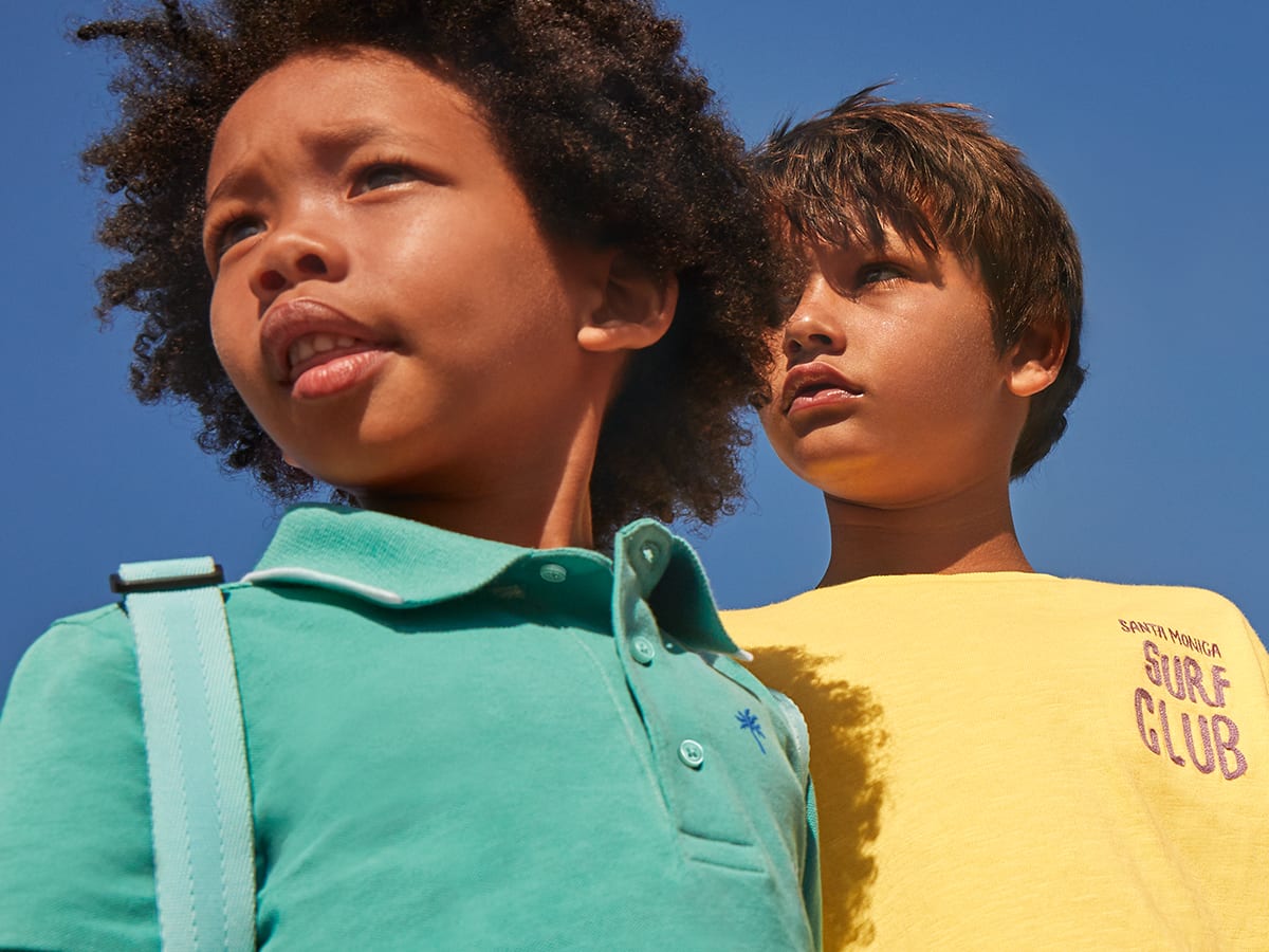 Boys in the sunshine, one wearing a green polo shirt and one a yellow T-shirt