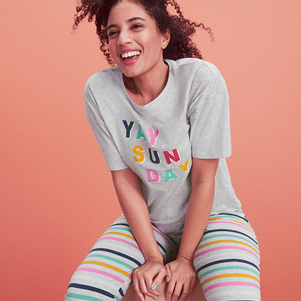 Woman wearing striped pyjama bottoms and graphic sleep tee