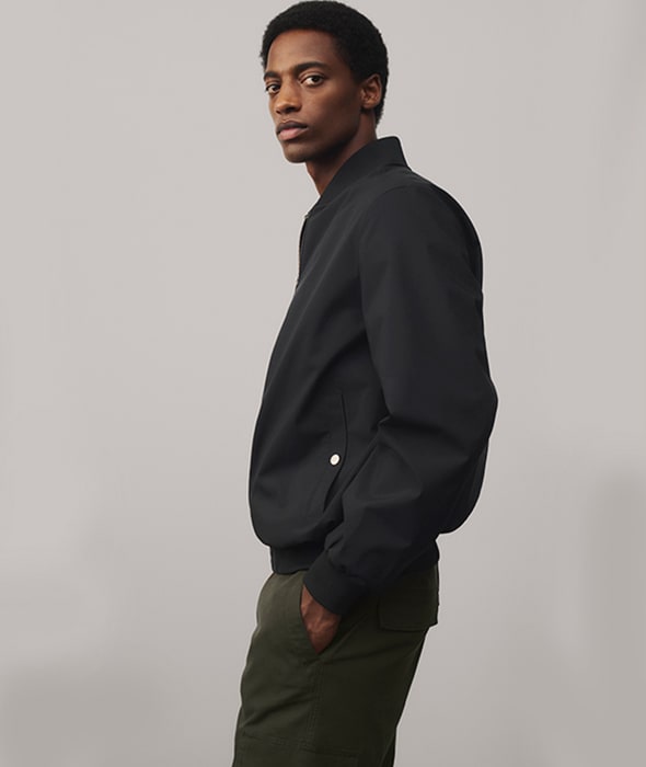 Man wearing a black jacket, khaki cargo trousers. Shop men’s everyday essentials