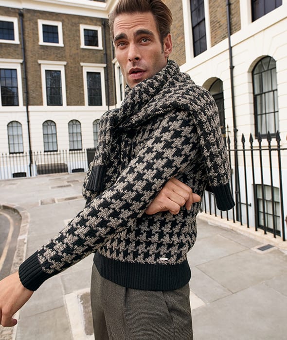 Man wearing black and light brown houndstooth crew-neck jumper and light brown puppytooth trousers