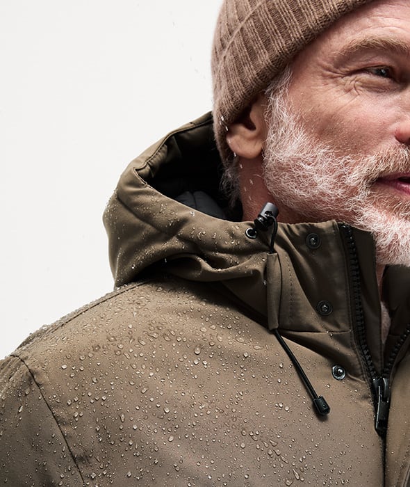 Man wearing waterproof padded parka jacket, jumper and beanie hat