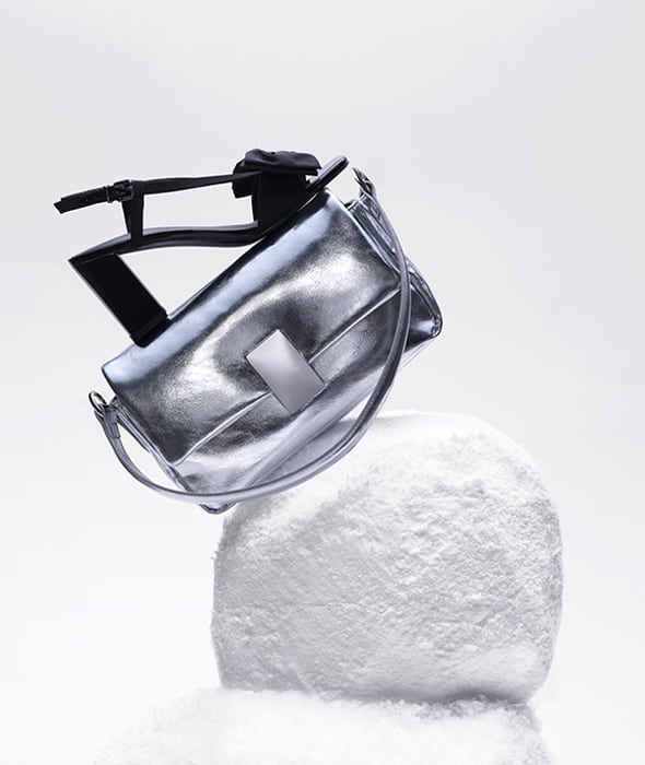 A silver bag and black shoe on a snow pile