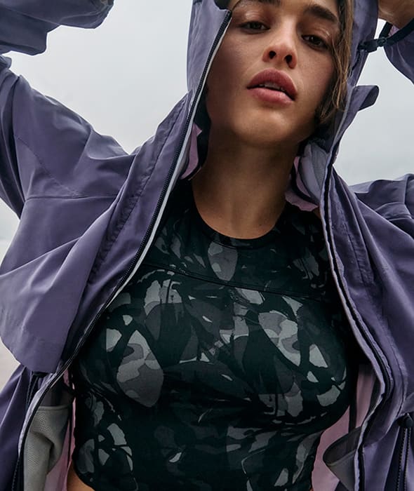 Woman wearing patterned sports bra and purple sports jacket