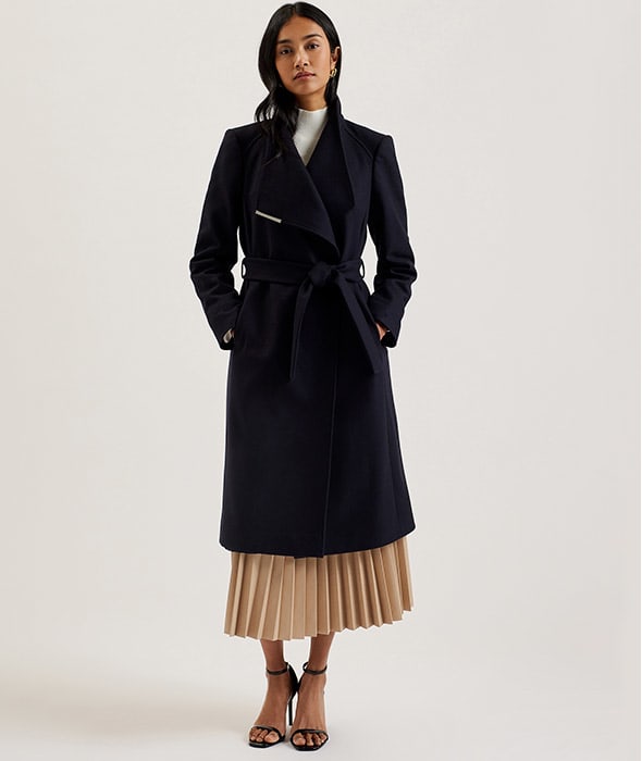 Woman wearing navy wrap coat and heels