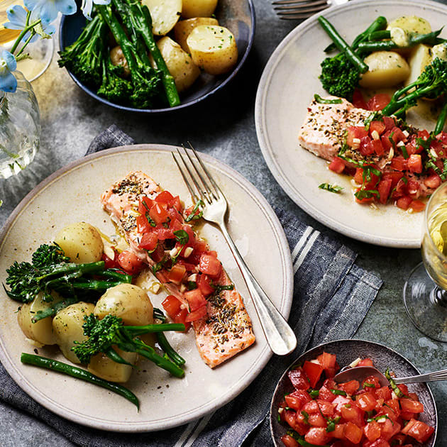 Plates of bruschetta salmon with jersey royals and green vegetables
