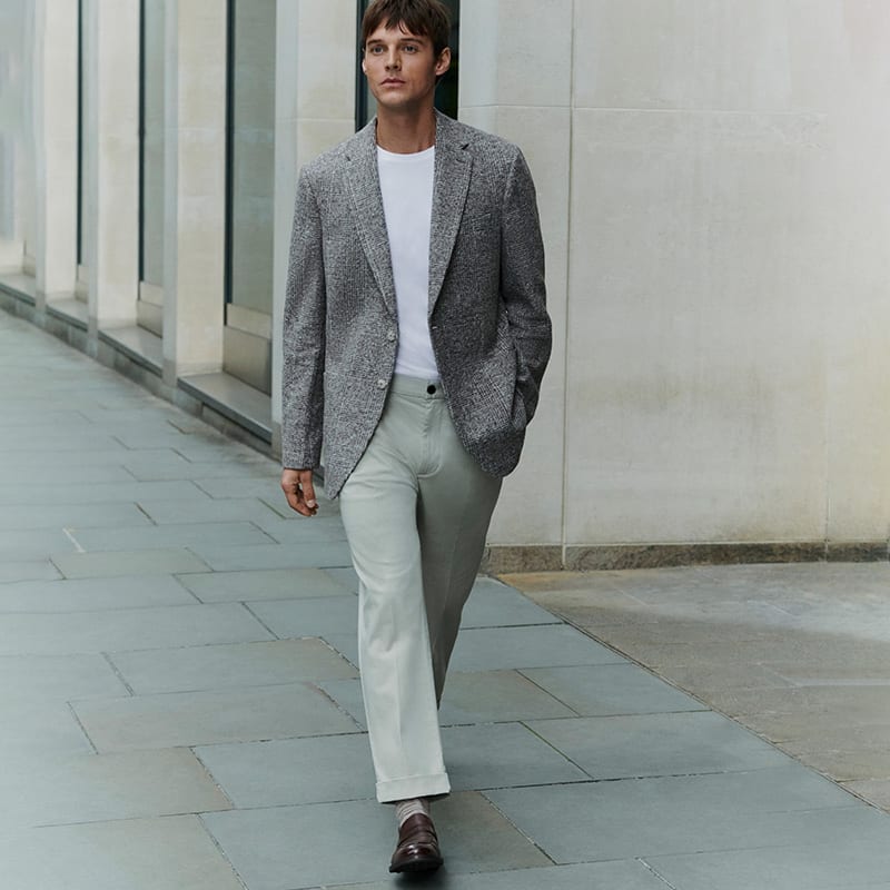 Man wearing grey slim-fit chinos and a textured check blazer. Shop slim-fit chinos