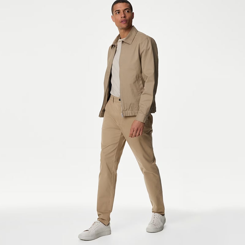 Man wearing tan tapered-fit cargo chinos, a T-shirt and a tan jacket. Shop tapered-fit chinos