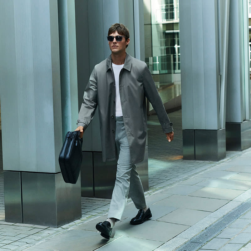 Man wearing light brown suit and black polo-shirt with black shoes. Shop men’s suits 