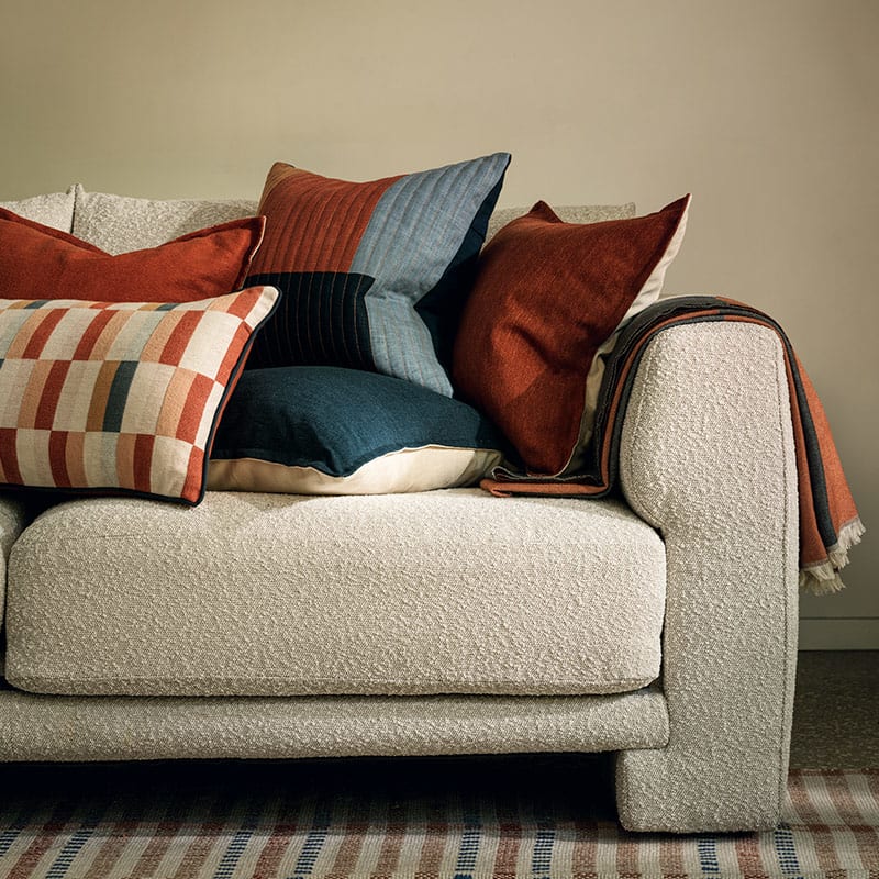 Assorted cushions in various colours on a sofa. Shop cushions