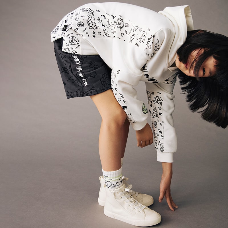 Girl wearing M&S x The Doodle Boy hoodie, shorts and socks. Shop M&S x The Doodle Boy