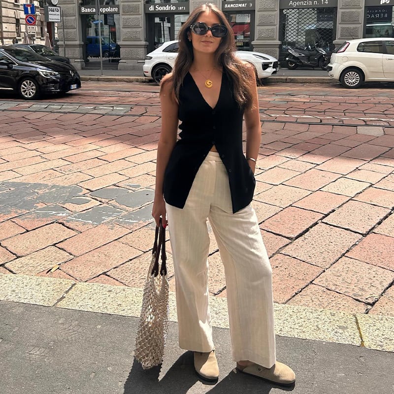 Instagram star Zarah Hameed (@marksandspencer_zarah) wears a black longline waistcoat, cream striped trousers, beaded bag and beige suede mules. Shop women’s waistcoats