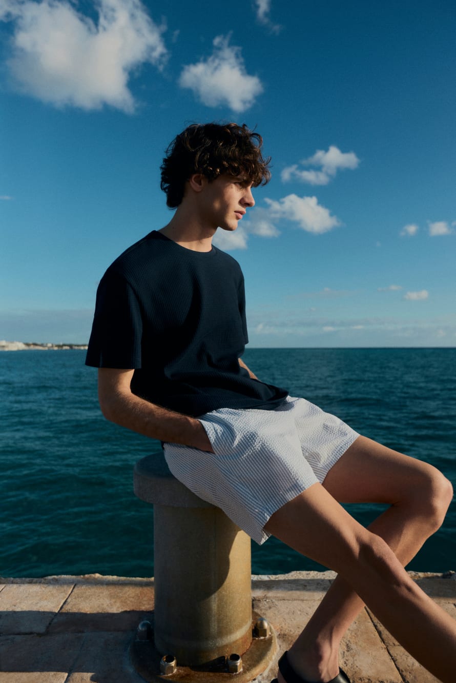 Young man sitting on a concrete post