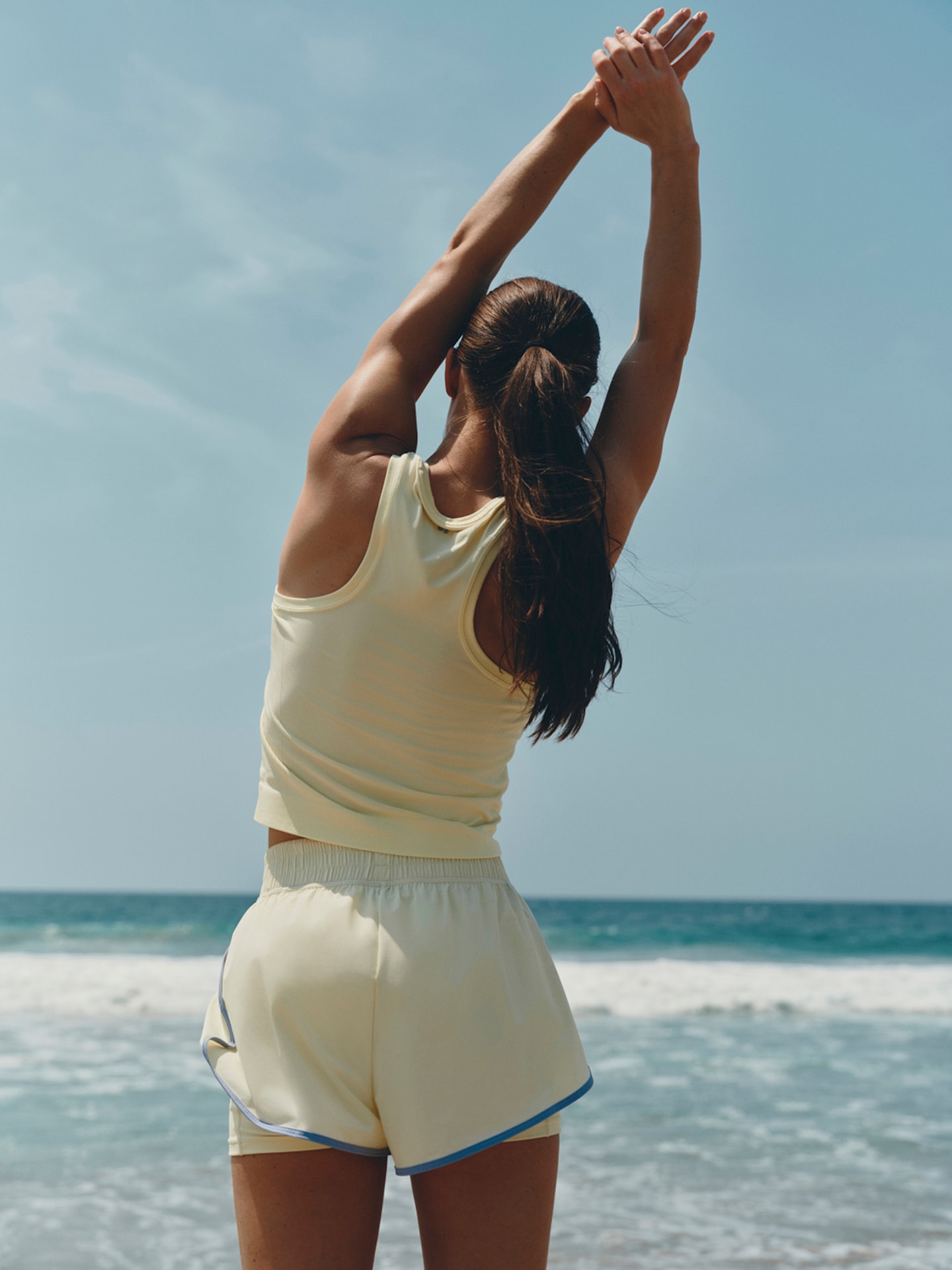 Woman stretching on a beach in yellow athletic wear