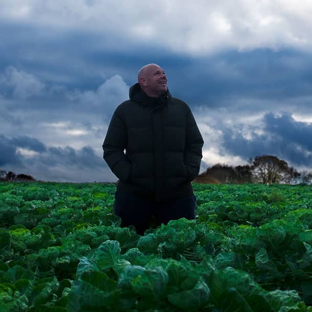 A picture of chef Tom Kerridge in a field smiling